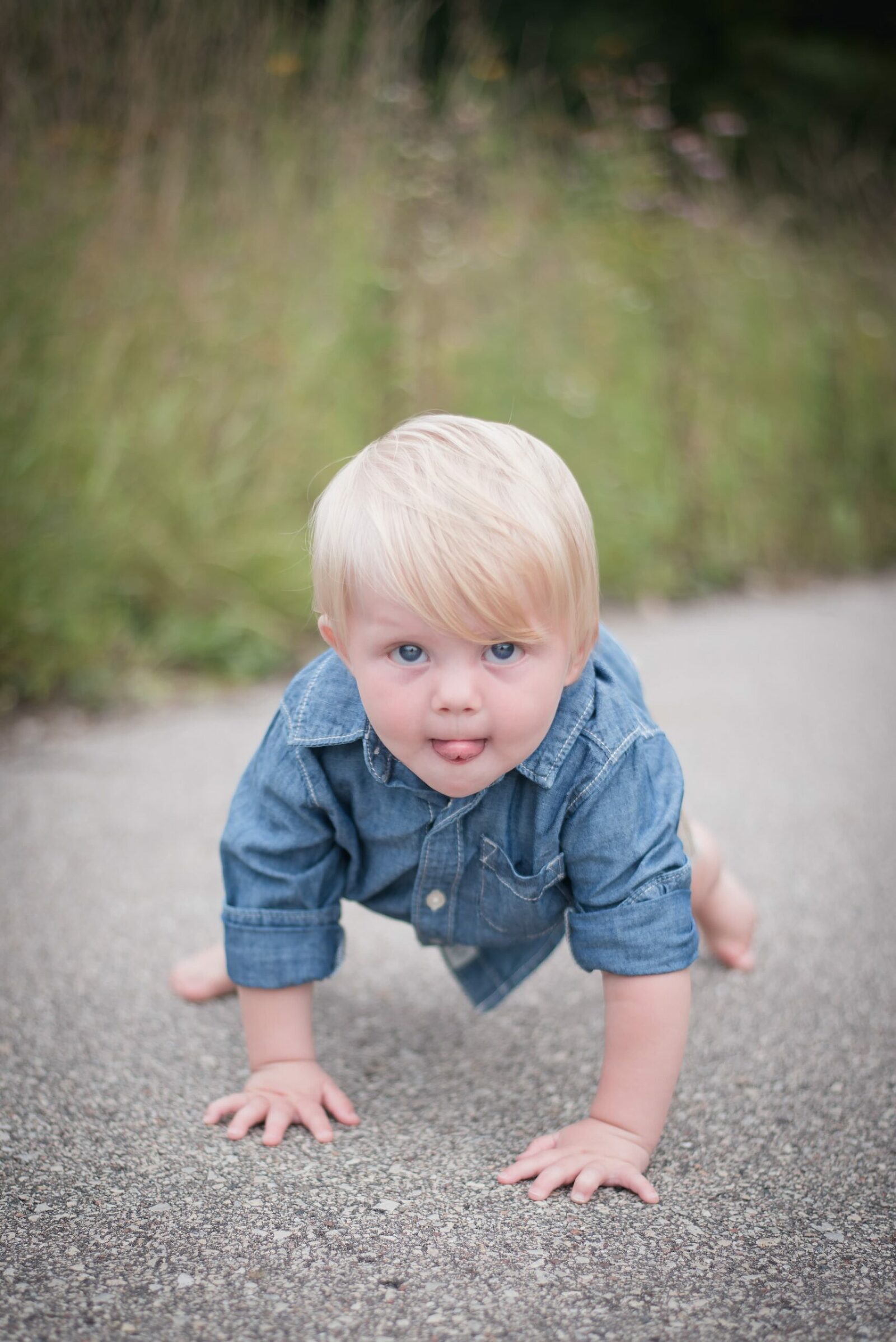 9 month old boy on all fours sticking out tongue looking at camera