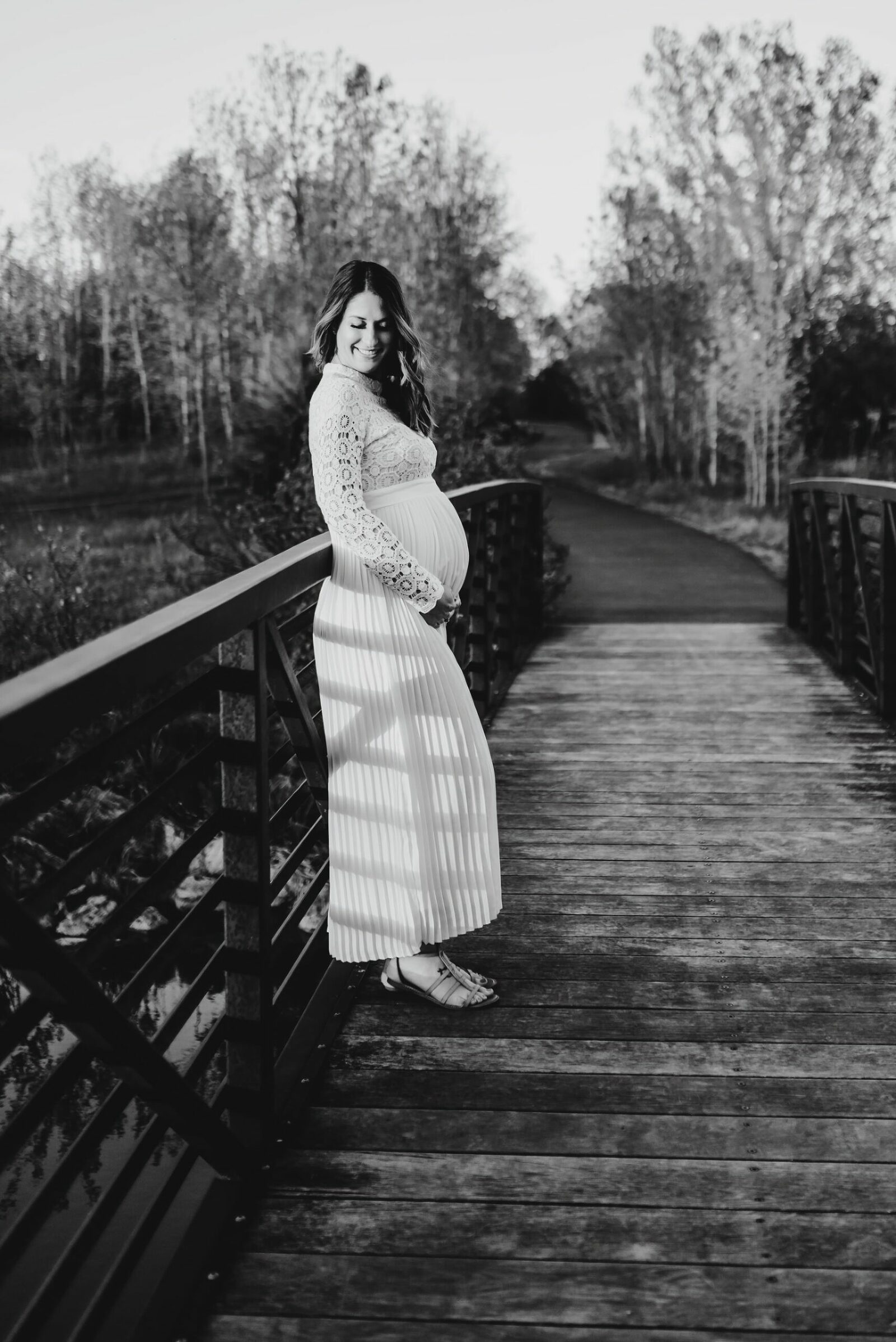 pregnant mother holding her belly on bridge in black and white