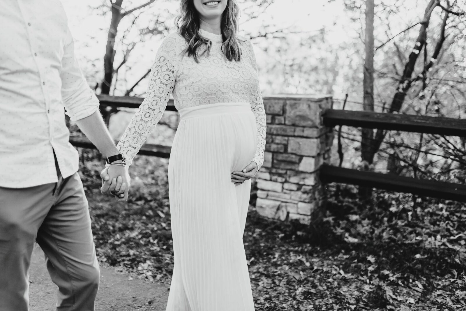 pregnant mother holding hands with father walking in black and white